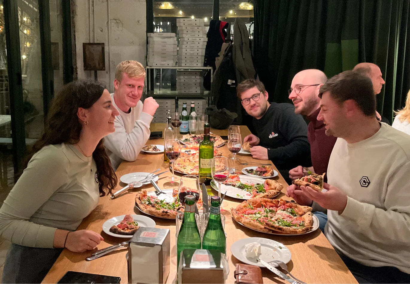 Five colleagues eating pizza at the table, having fun